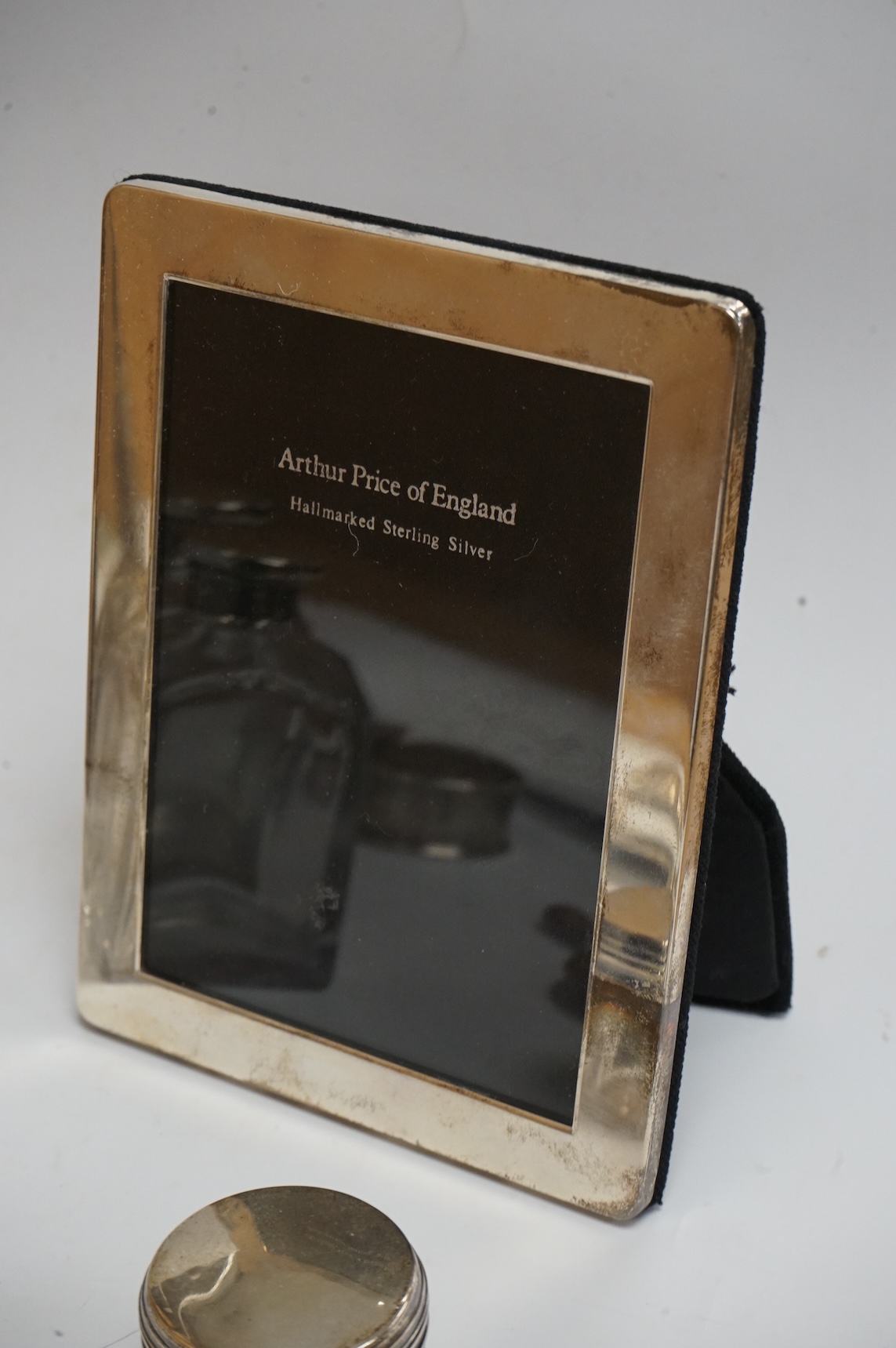 A late Victorian repousse silver mounted rectangular easel mirror, Birmingham, 1896, 35.7cm(a.f.), together with a modern silver mounted photograph frame, a silver handbag mirror/compact, three mounted glass toilet jars,